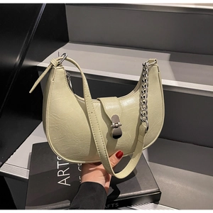 Détail du sac croissant vert clair avec chaîne argentée et texture de cuir plissé chic