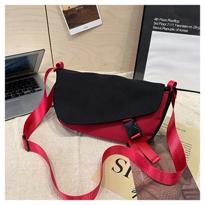 Detail of red and black messenger bag with adjustable strap and buckle in a lifestyle setting