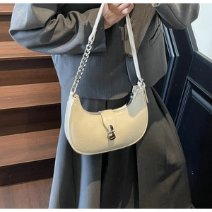 Gros plan du sac demi-lune crème avec boucle en métal argenté et bandoulière chaîne