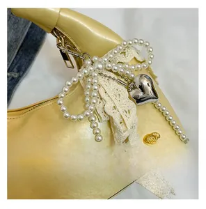 Detail of yellow crescent bag with pearl bow, lace ribbons and metal heart charm
