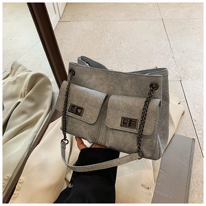 Detail of gray denim crossbody bag with dual quilted pockets and vintage metal buckles