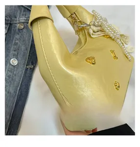 Detail of cream leather bag featuring pearl chain and gold heart-shaped metal charms