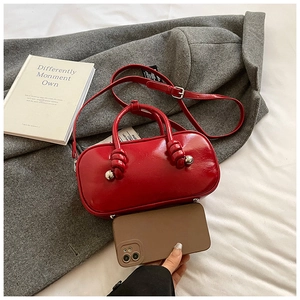 Détail du mini sac en cuir verni rouge avec poignée nouée et ornement boule argent