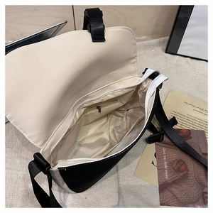 Interior view of black and white crossbody bag showing zipper pocket and inner compartments