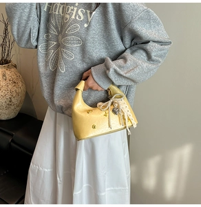 Detail of pale yellow crescent handbag with pearl chain, lace bow, and floral metal buckle