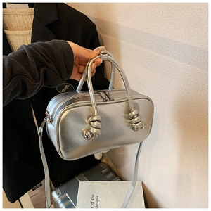 Détail d'un sac à main argenté métallisé avec poignées nouées et double fermeture