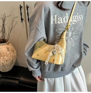 Detail of cream saddle bag with lace pearl bow charm and heart pendant decoration