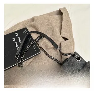 Close-up of quilted grey denim bag with vintage silver chain and leather shoulder strap
