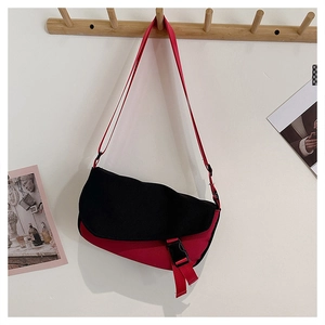 Detail of color-block messenger bag with black buckle and adjustable red strap
