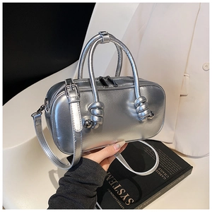 Sac à main argenté métallisé minimaliste avec poignée nouée et double zip tenu à la main