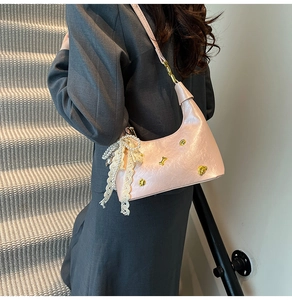 Detail of pink hobo bag featuring lace pearl bow charm and gold bear metal accents