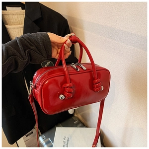 Détail d'un sac à main rouge en cuir verni brillant avec une poignée artistique nouée