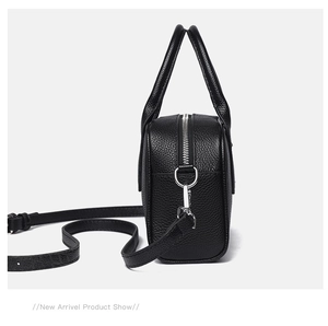 Side view of black lychee grain leather bowling bag with silver zipper and shoulder strap