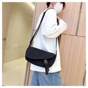 Classic black canvas messenger bag worn crossbody with flap cover and buckle detail