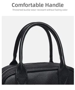 Detail of double cylindrical handles and pebbled leather texture on black bowling bag