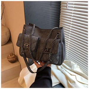 Detail of grey canvas tote bag featuring quilted pockets and metal chain strap