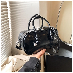 Détail d'un sac Boston en cuir verni noir brillant avec poignées rondes et boules argentées