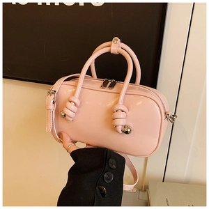 Détail du sac cylindrique rose brillant avec poignées nouées et détails en billes argent
