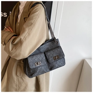 Detail showing the gray quilted denim fabric and dual front flap pockets with chain strap
