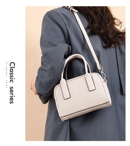 Detailed back view of a white leather crossbody bag worn over a grey blazer jacket