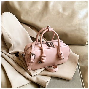Détail d'un mini sac rose en cuir brillant avec poignée nouée et bouclerie argent