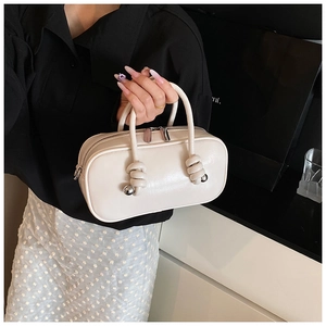 Détail du sac carré crème avec poignée nouée et ornement de boule en métal chic