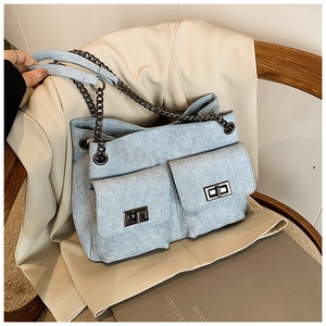 Detail of light blue quilted denim tote bag with chain strap and metal turn-lock pockets