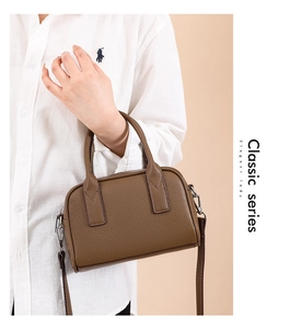 Detail of a brown lychee pattern leather bowling bag with twin handles and strap