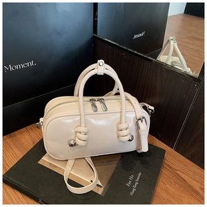 Détail du sac Boston verni crème avec poignée nouée et sphères métalliques argentées