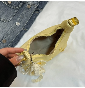 Detail of yellow dumpling bag with pearl charm and white lace bow decoration
