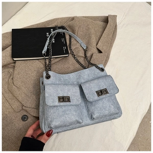 Detail of light blue quilted bag with front pockets and gunmetal twist-lock fasteners