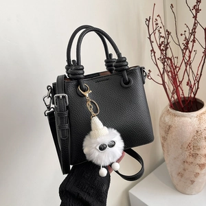 Minimalist black lychee leather crossbody bag with knot handles and cute plush charm