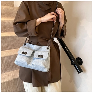 Detail of light gray tweed crossbody bag with double front pockets and metal turn-locks