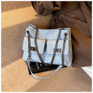 Detail of light blue textured shoulder bag with double pockets and metal chain strap
