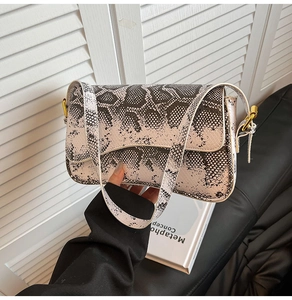 Détail de la texture serpent en similicuir avec boucle dorée sur un petit sac carré