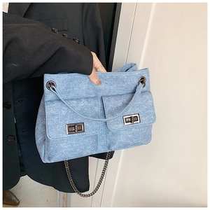 Detail of light blue quilted denim bag with twin front pockets and chain strap