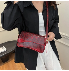 Détail de la texture serpent rouge et noir et boucle dorée sur un sac à bandoulière