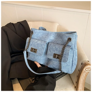 Detailed texture of blue denim chain bag with rhombic stitching and metal turn-locks