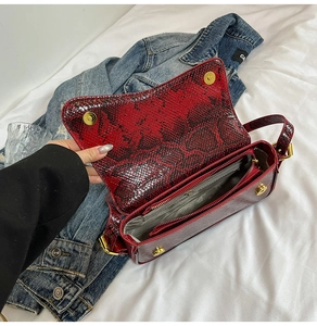 Détail du sac à main rouge à motif serpent avec double rabat magnétique et ferrures dorées