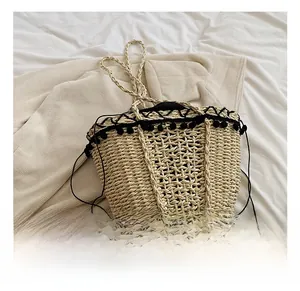 Close-up of handmade straw tote bag featuring black pom-pom trim and drawstring closure
