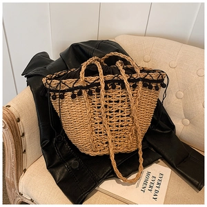 Detail of woven straw bag featuring black pom-pom trim and a drawstring liner