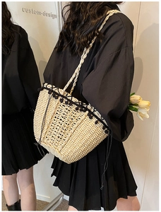 Detail of hand-woven straw shoulder bag with black lace trim and pom-poms for beach travel