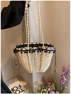 Detail of straw handbag featuring black pom-pom trim and secure drawstring lining