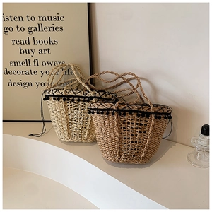 Detail of handmade straw tote bag with black pom-pom trim and rustic woven texture