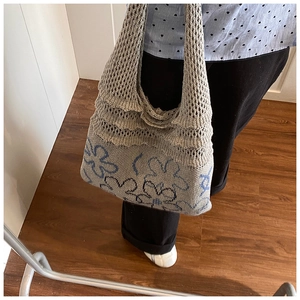 Detail of grey knitted tote bag with large blue and black floral embroidery on base