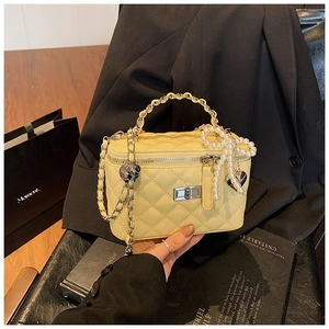 Detail of light yellow quilted box bag featuring silver twist lock and pearl heart charm