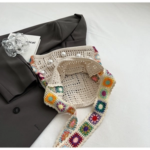 Detail der Boho-Stricktasche mit buntem Häkelriemen und eleganten Perlenverzierungen