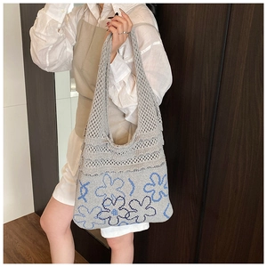 Detailed texture of grey knit tote bag featuring blue floral print and mesh hollow design