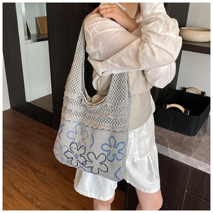 Close-up of soft knit shoulder bag featuring blue floral patterns and hollow mesh structure