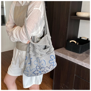 Detailed macro view of gray knitted tote bag with blue floral patterns and ruffle trim